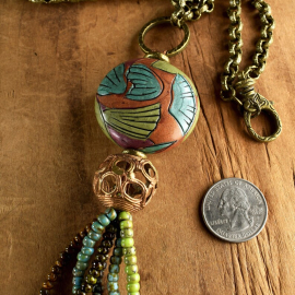 Colorful beaded tassel pendant with long chain by Gloria Ewing.